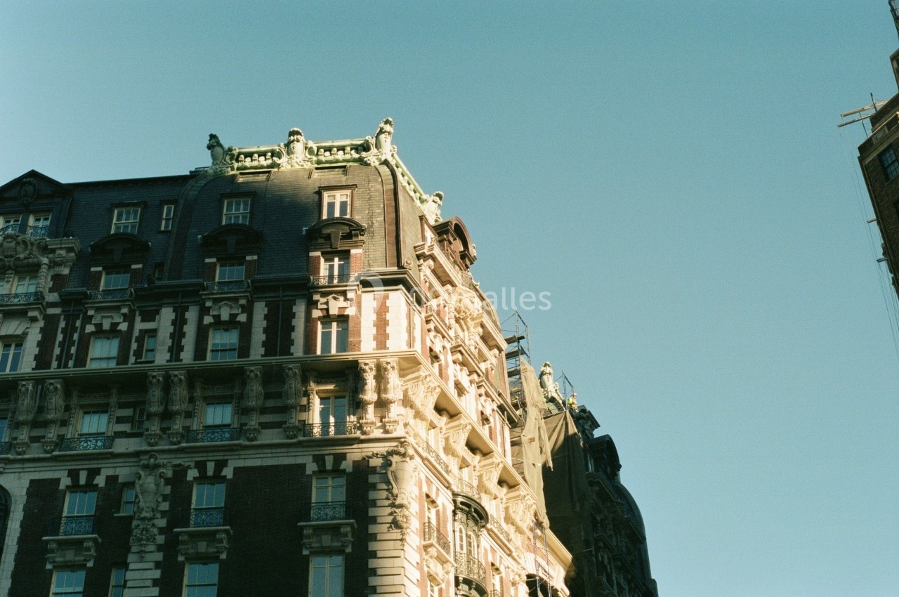 Façade d'un immeuble ancien avec des détails architecturaux ornés, sous un ciel dégagé.